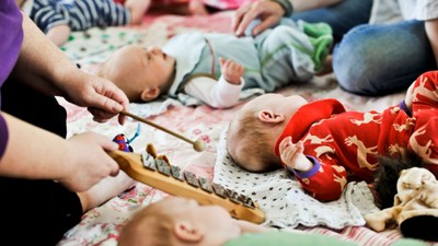 En gruppe børn spiller med på en dekke, mens en voksende hold en marke.