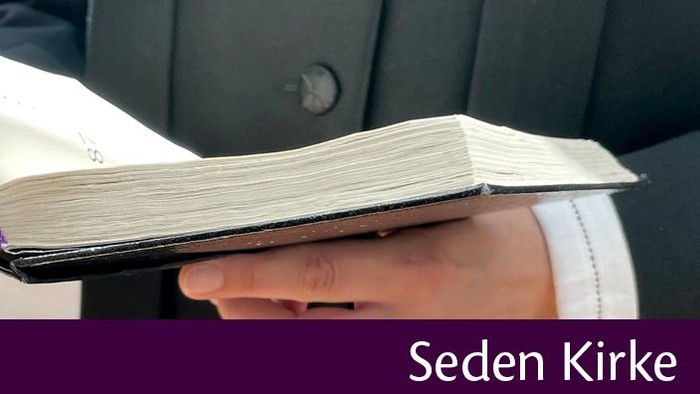 En person holder en åben bog i hånden.