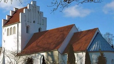 Et hvidt kirkebygningskompleks med røde tag og en tårn.