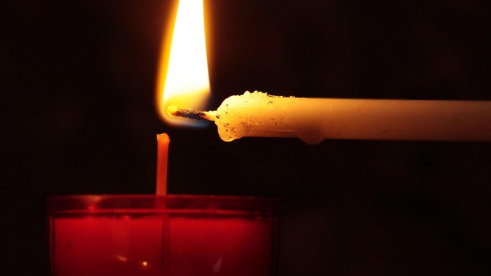 Eine brennende Kerze in einem roten Halter.