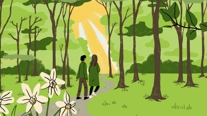 To mennesker spadserer hånd i hånd ad en fredfyldt skovsti omkranset af blomstrende blomster og høje træer.