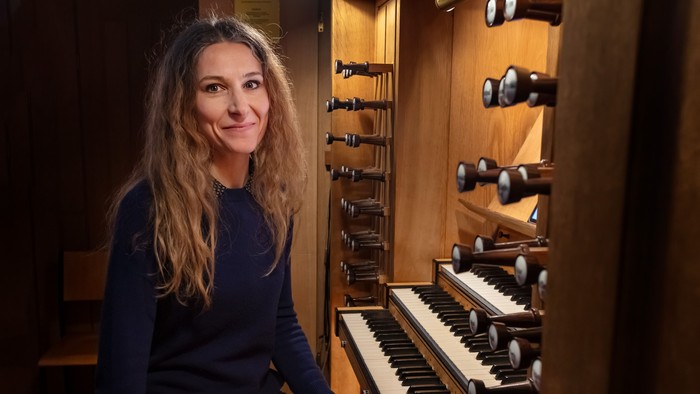 Kvinde sitter ved et orgel og smiler.