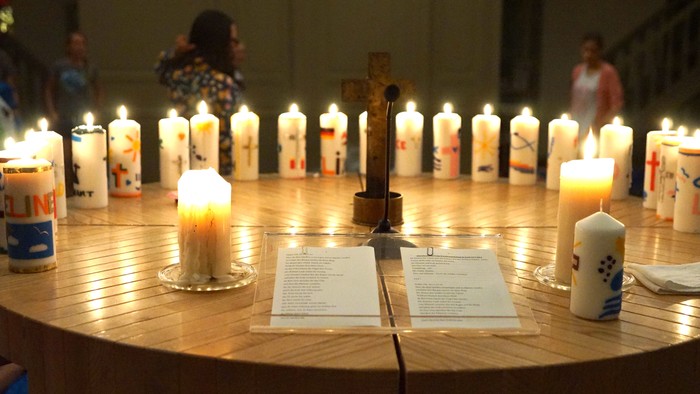 Ein Tisch mit vielen brennenden Kerzen und einem Mikrofon darauf