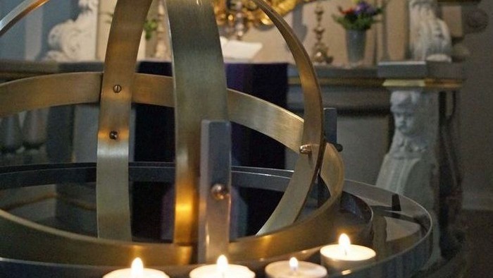 Ein metallener Globus mit brennenden Kerzen in einer Kirche