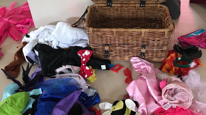 Überall verstreute Kleidung und Accessoires um einen Korb.