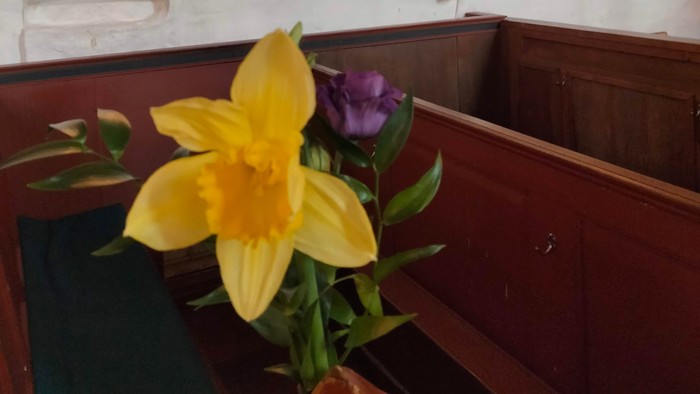 En blomsterstang med gule og lilla blomster på alteret i kirken