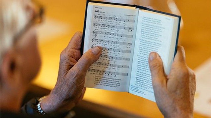 En person holder en noterbog med noter og tekst.