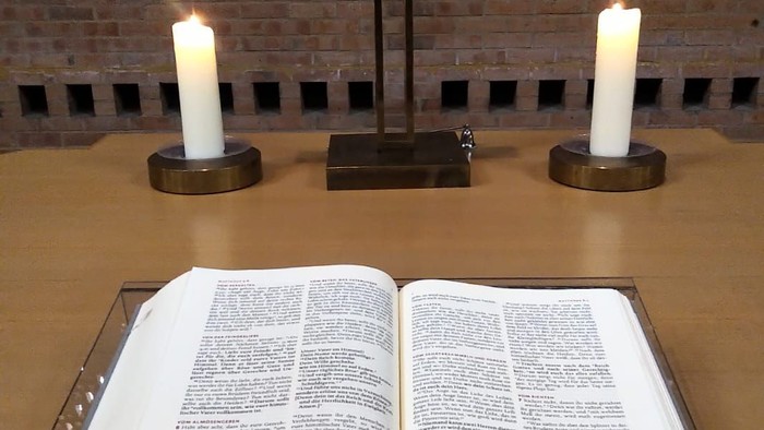 Offene Bibel mit Kreuz und Kerzen