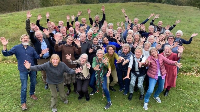 En stor gruppe af glade og lyse mennesker samlet på en grøn eng