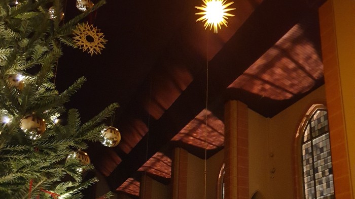 Ein geschmückter Weihnachtsbaum vor einem Kirchenfenster