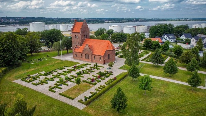 En rød kirke med have og vej til havnen