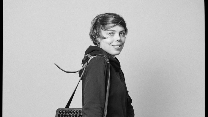 Frau mit Akkordeon, trägt eine Brille und Turnschuhe.