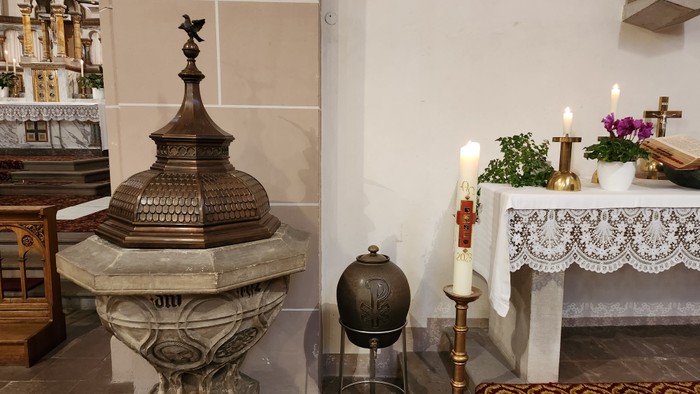 Altar mit Kerzen, Kelch und Blumenschmuck in Kirche
