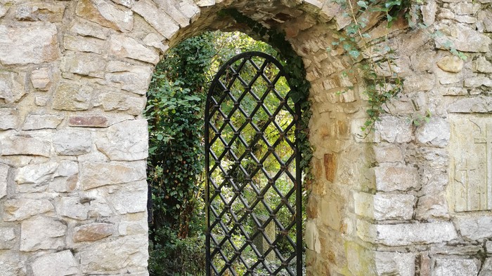 Ein alter Steinbogen mit einem schwarzen schmiedeeisernen Tor.