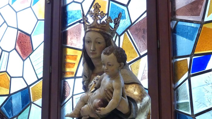 Heilige Muttergottes Statue vor buntem Kirchenfenster