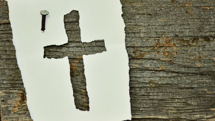 Ein Nagel und ein Kreuz auf einem Baumstamm.