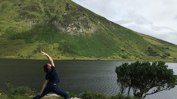 Frau übt Yoga am See in den Bergen