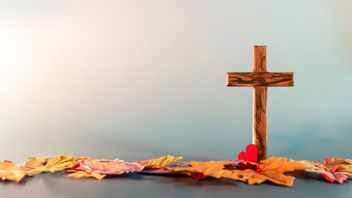 Holzkreuz mit Herbstblaettern und kleinem Herz