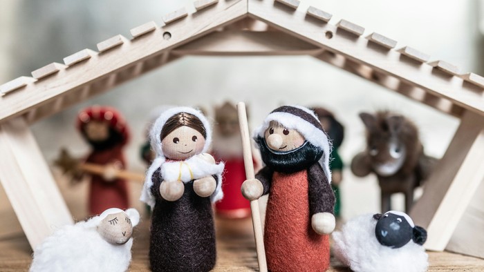 Eine Miniatur-Naturszene mit Holzfiguren, darunter Maria, Josef, das Jesuskind, ein Esel und eine Kuh.