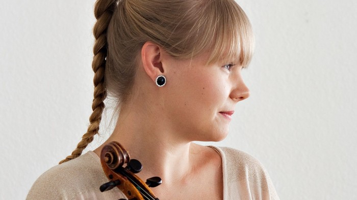 En kvinde, der holder en violin, med håret flettet i en fletning.