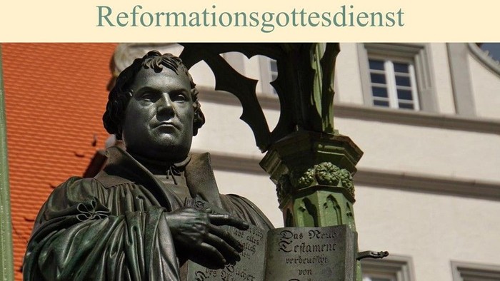 Statue eines Mannes mit Buch, Reformationsthema, Gebäude im Hintergrund