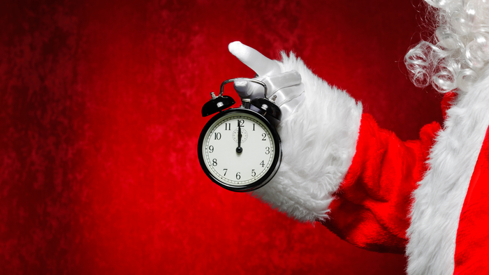 Santa Claus hält eine schwarze Uhr mit weißem Zifferblatt hoch.