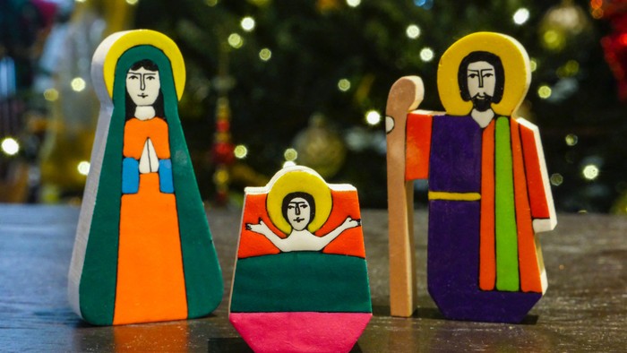 Drei bunte Holzfiguren vor Weihnachtsbaum