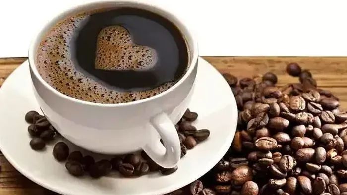 En kaffe i tæppe med hjerteformet skum og kaffebønner på bordet