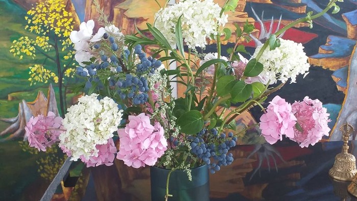 En blomsterstang med hvide og rosa blomster foran et maleri