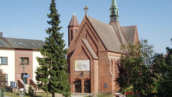 Kirchengelände mit Kopfsteinpflasterweg und Bäumen