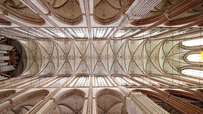 Die Decke einer gotischen Kirche mit aufwendigen Stuckarbeiten und hohen Bögen.