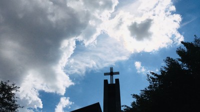 Kirchturm vor blauem Himmel mit Wolken
