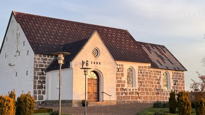 Stenkirke med rødt tag og grussti