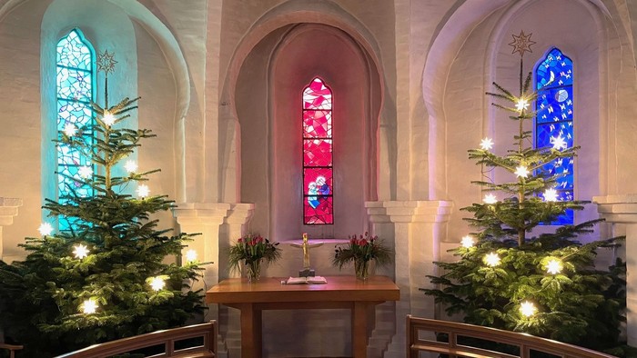 To alter i kirken med tre juletænder med lys og farverige vinduer
