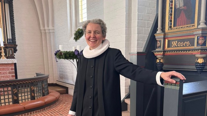 Kvinde i sort kåbe står ved orglet i kirken.