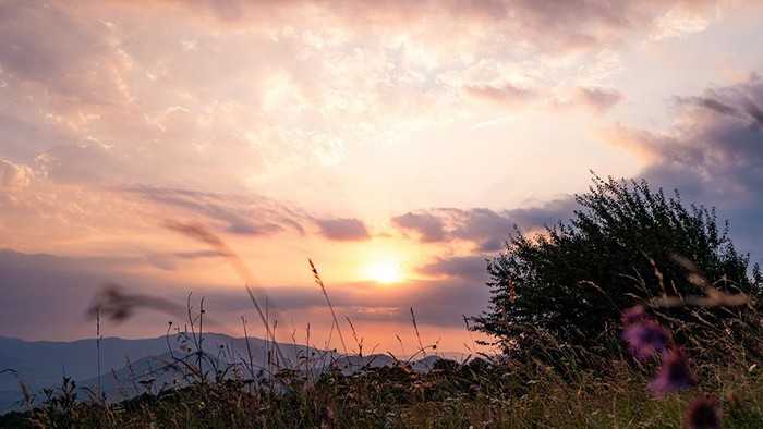 Sonnenuntergang über einer ruhigen Landschaft mit Wolken.