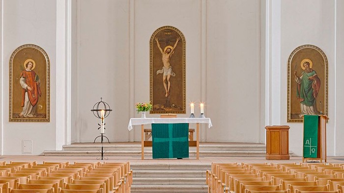 Die Kirche mit Holzstühlen und Altarraum mit religiösen Bildern