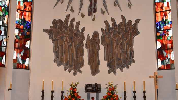 In der Kirche: Altar mit Kreuz, Kerzen und Blumen.