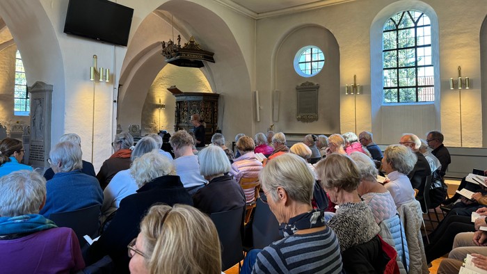 En kirke med mange mennesker, der deltager i en gudstjeneste.