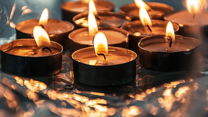 Mehrere brennende Teelichter in schwarzen Behältern