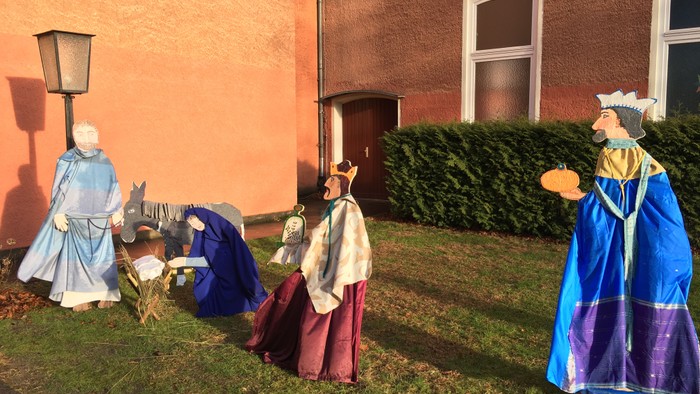 Figuren vor orangefarbenem Haus mit Laterne und Fenster