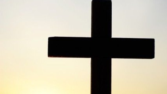 En sort korsformet silhuet foran solnedgang