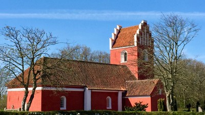 Rødt kirke med tårn og tagtegn i træ.
