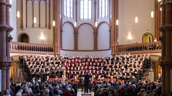 Ein großer Kirchenchor singt vor einem großen Publikum in einer prächtigen Kathedrale.