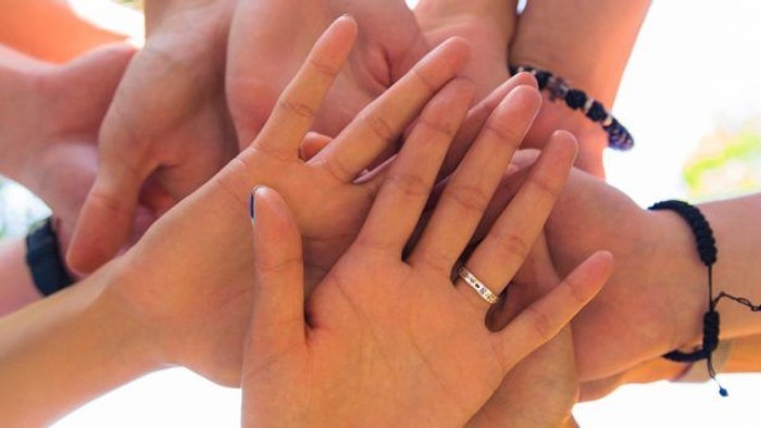 Ein Team von Menschen bildet einen Kreis mit den Händen, um ihre Einheit zu symbolisieren.