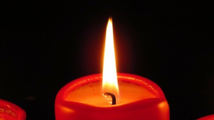 Eine rote Kerze brennt im Dunkeln.