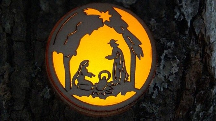 Ein beleuchtetes Holzschilder mit der Darstellung der Krippe.