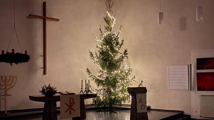 Weihnachtsbaum in der Kirche mit Kreuz und Kerzenleuchter