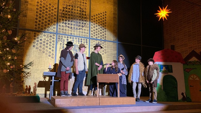Eine Gruppe von Menschen steht auf einer Bühne und singt Weihnachtslieder.