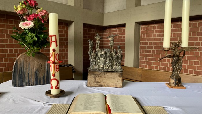 Ein Altar mit Kerzen, Blumen und einem aufgeschlagenen Buch